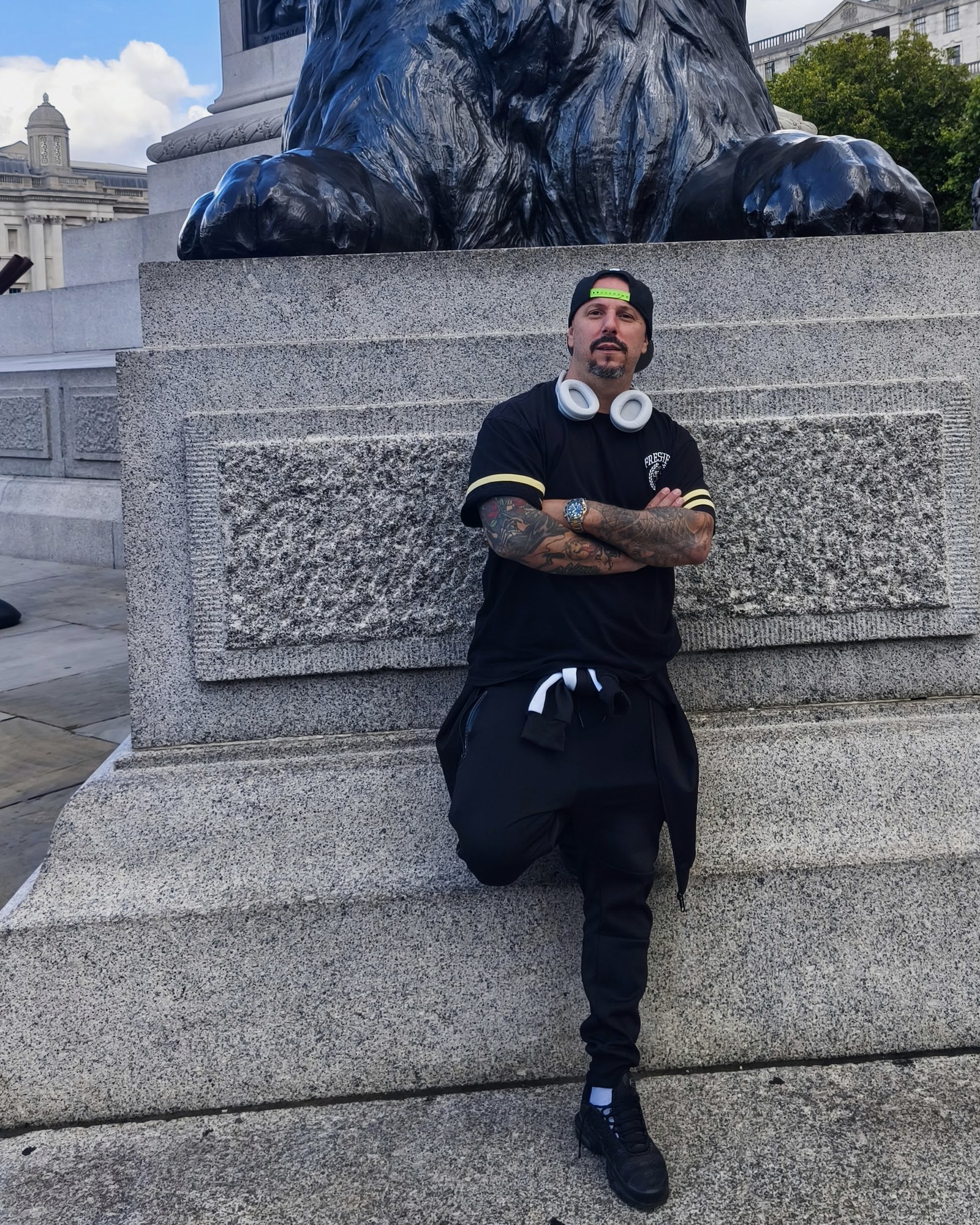 Retrato de Enrique (FUNESMA79), brazos cruzados, junto a uno de los leones de Trafalgar Square