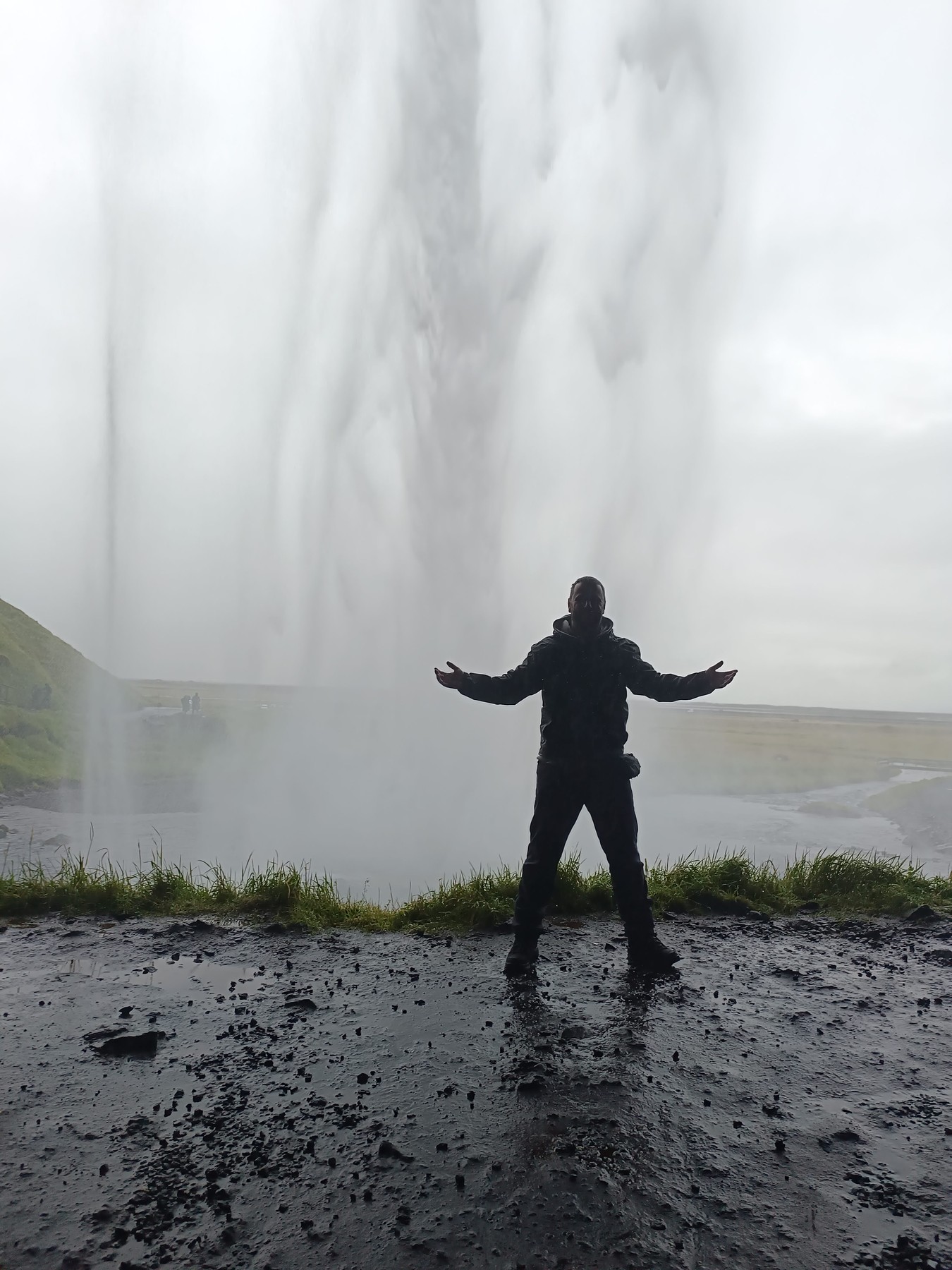 Enrique con los brazos abiertos frente a una gran cascada