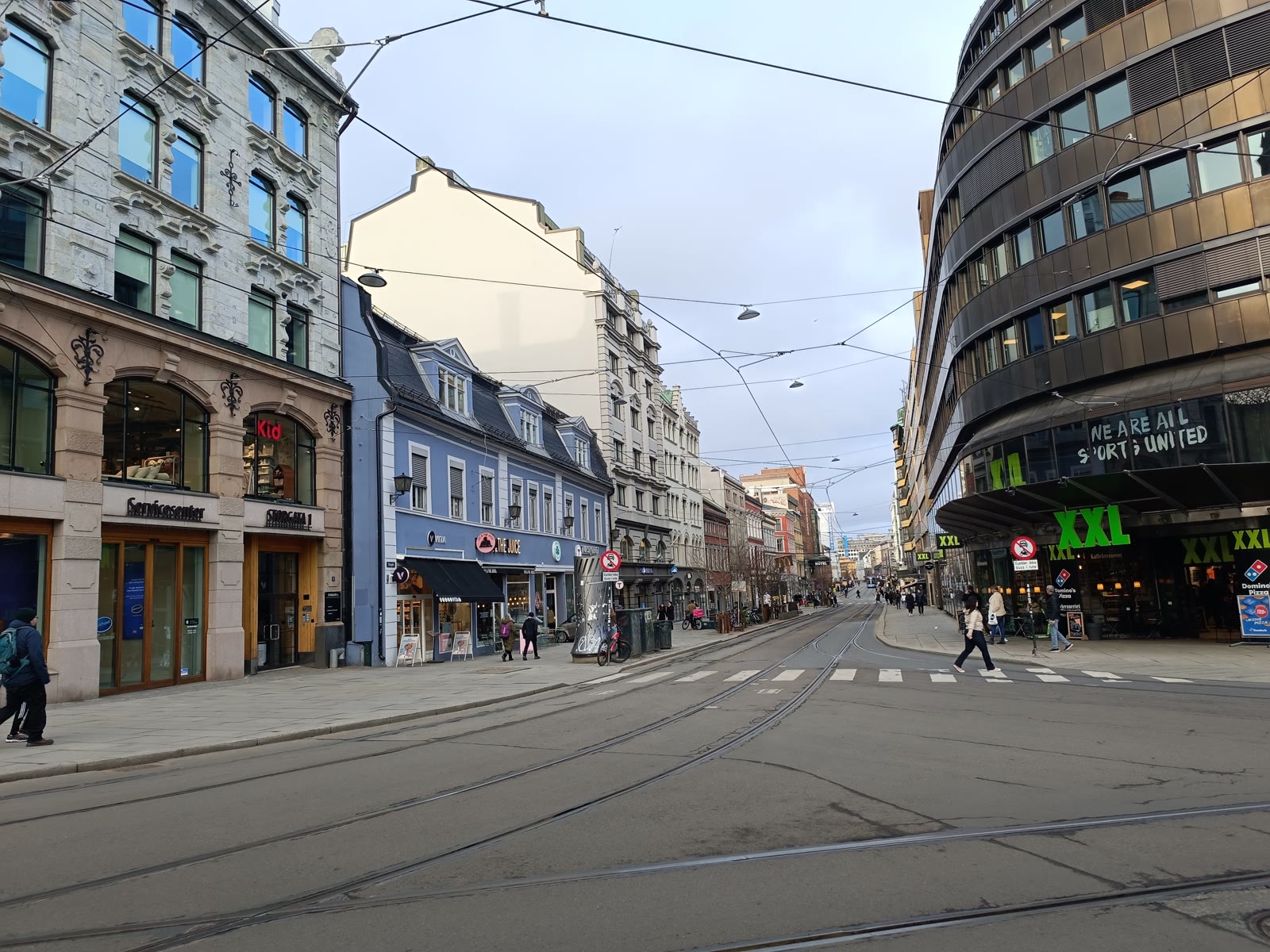 Calle urbana con tranvía, edificios históricos y arquitectura contemporánea al inicio del viaje