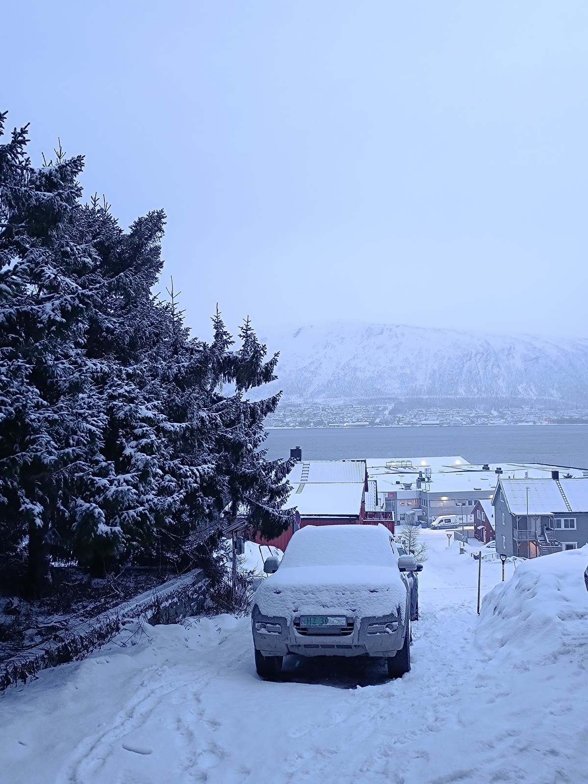 Calle cubierta de nieve junto al agua y las montañas durante el viaje por Noruega y Finlandia