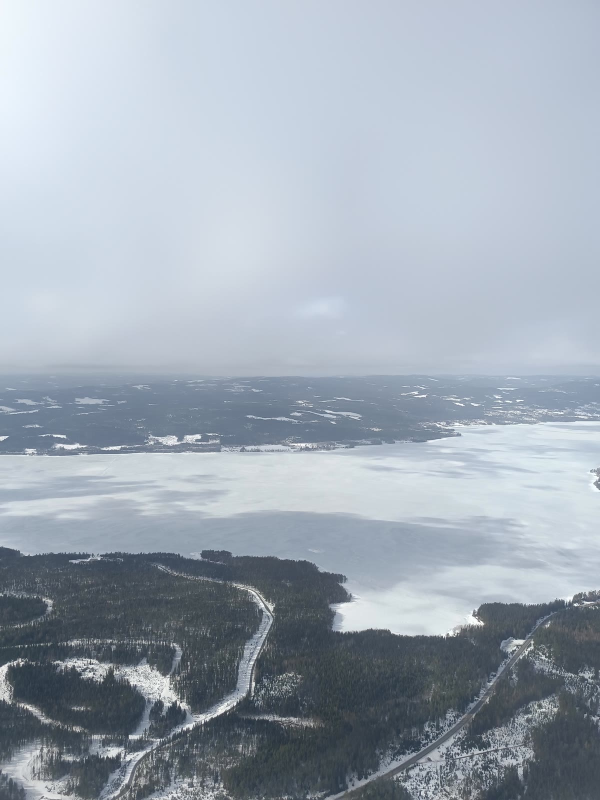 Vista elevada de un gran paisaje helado rodeado de bosques y carreteras nevadas
