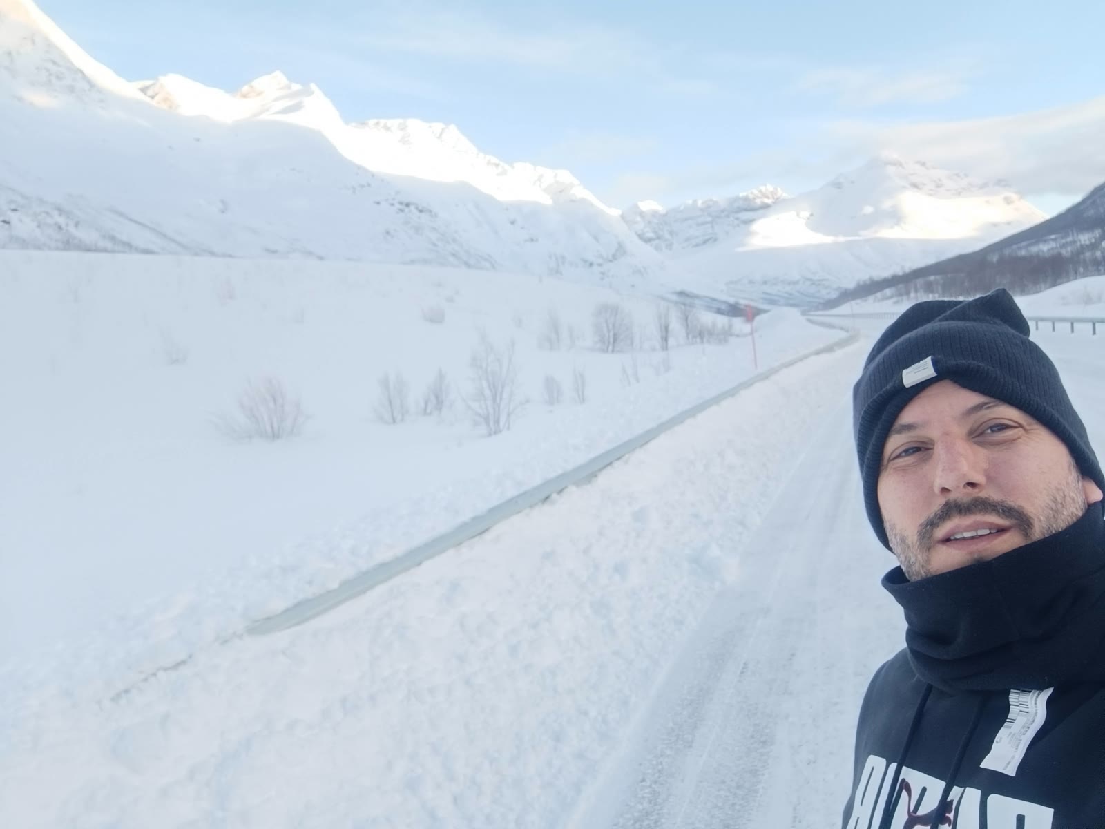 Autorretrato de Enrique junto a una carretera rodeada de montañas nevadas